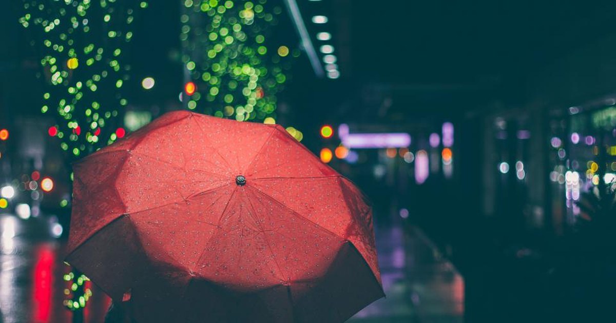 A red umbrella in the rain at night on a lit street: risk management in trading is the protection you decide on before the storm arrives